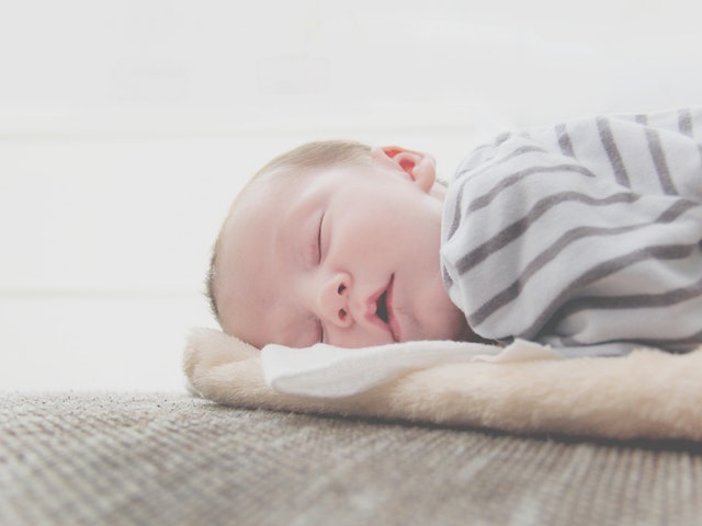 Malé bábätko, zakryté sivou dekou spí.jpg