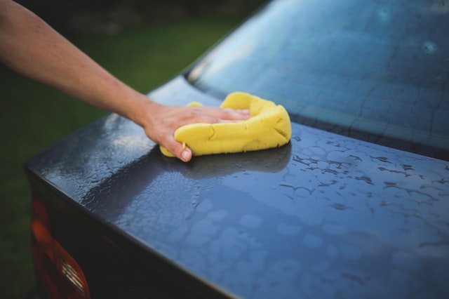 Muž umývajúci auto so žltou špongiou.jpg